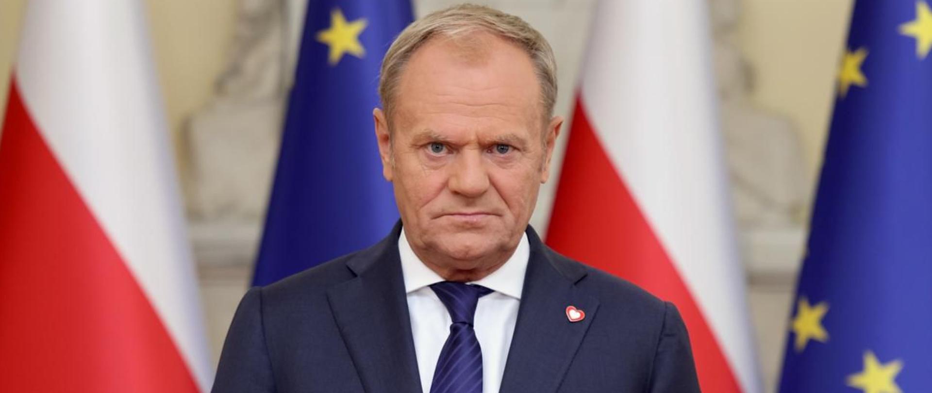 Premier Donald Tusk podczas wystąpienia 2 czerwca 2025 r. W tle flagi Polski i Unii Europejskiej.